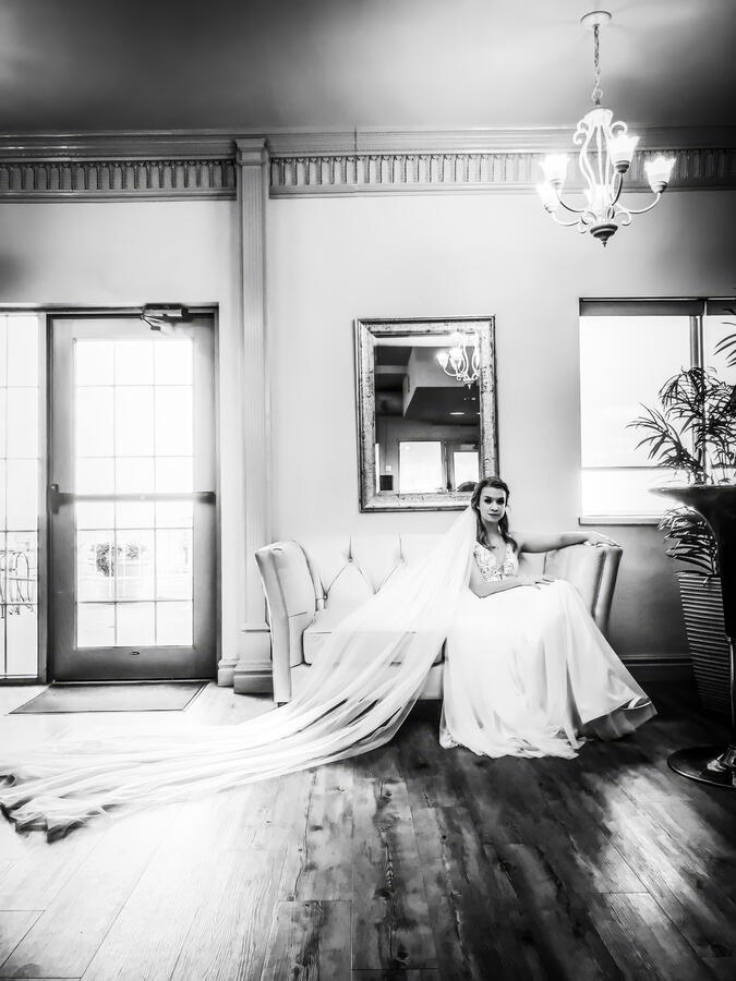 Untitled Bride sitting on old style chair with veil extended behind her