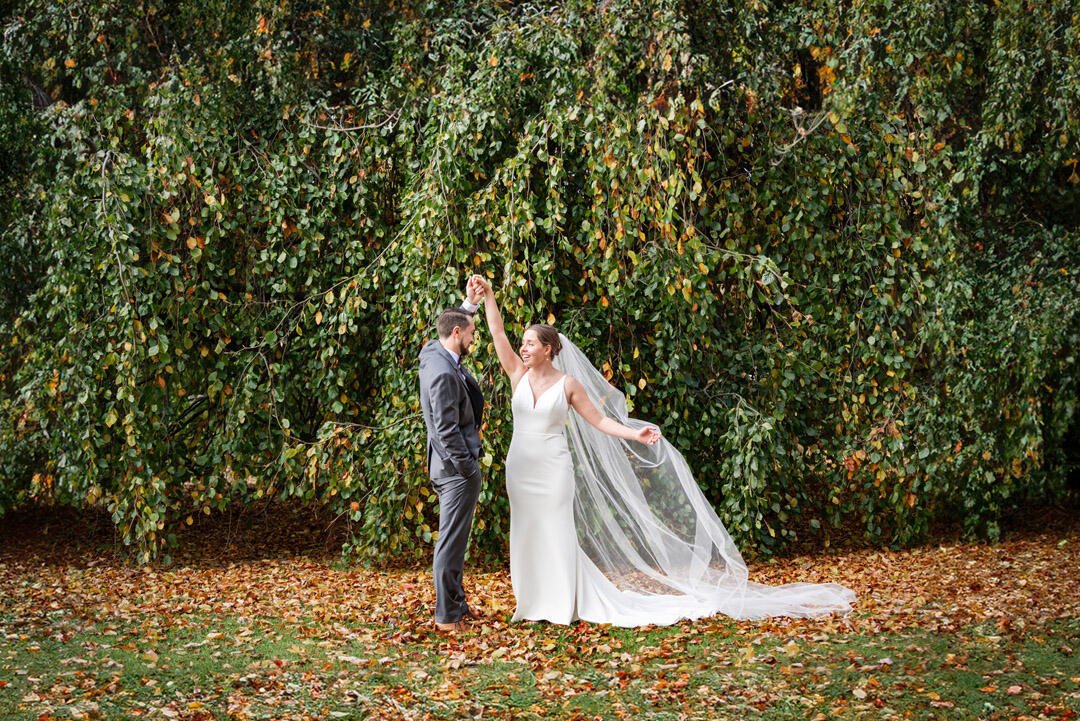 Untitled Groom twirling bride in front of a wall of greenery