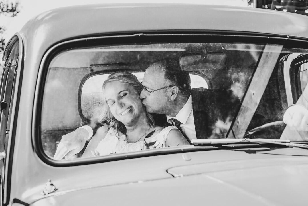 Untitled Wedding - Bride & Groom in a car, with groom kissing brides cheek