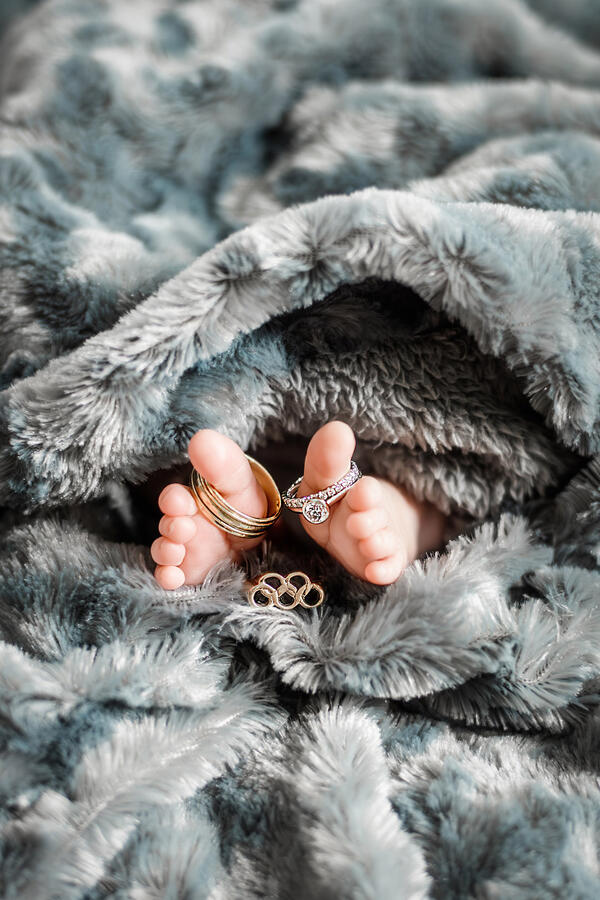 Untitled Baby - newborn toes surrounded by blanket, with wedding rings + olympic ring on toes