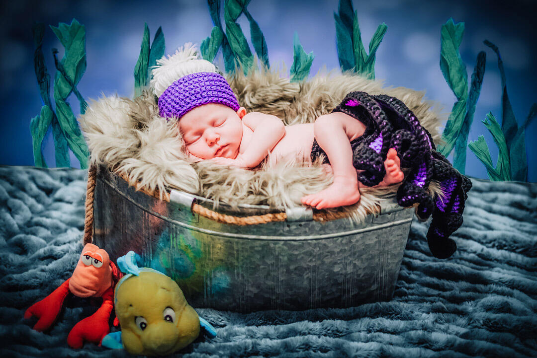 Untitled Baby - newborn wearing ursula crochet hat and diaper cover, sleeping with a sea backdrop